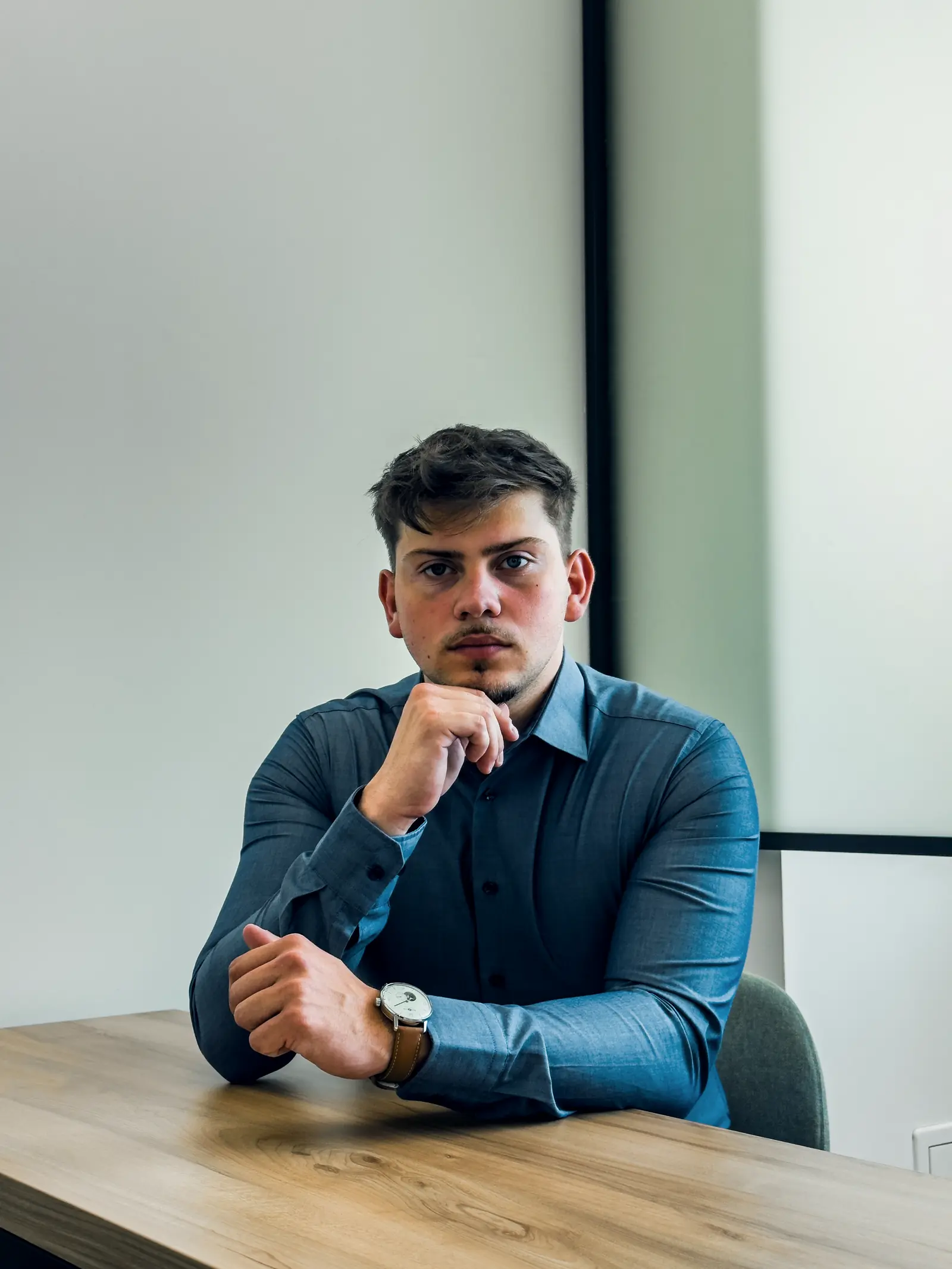Tudor Costin așezat la o masă de lucru, cu mâna la bărbie